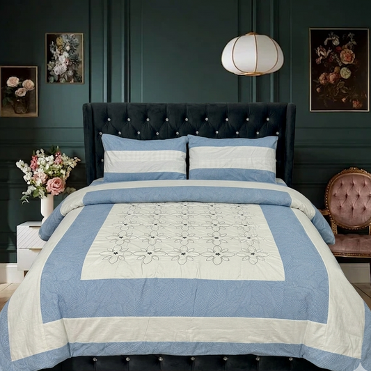 Blue and white quilt on a bed in a bedroom with dark green walls and floral decorations.