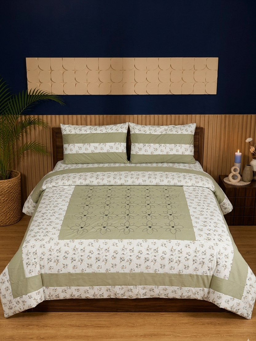 Bed with green and white floral patterned bedding against a dark blue wall.