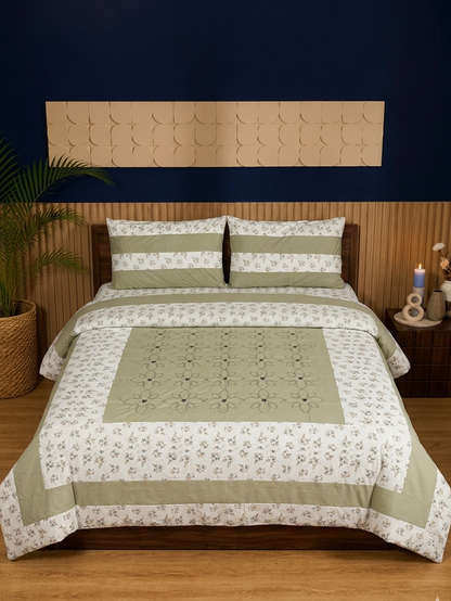 Bed with green and white floral patterned bedding against a dark blue wall.
