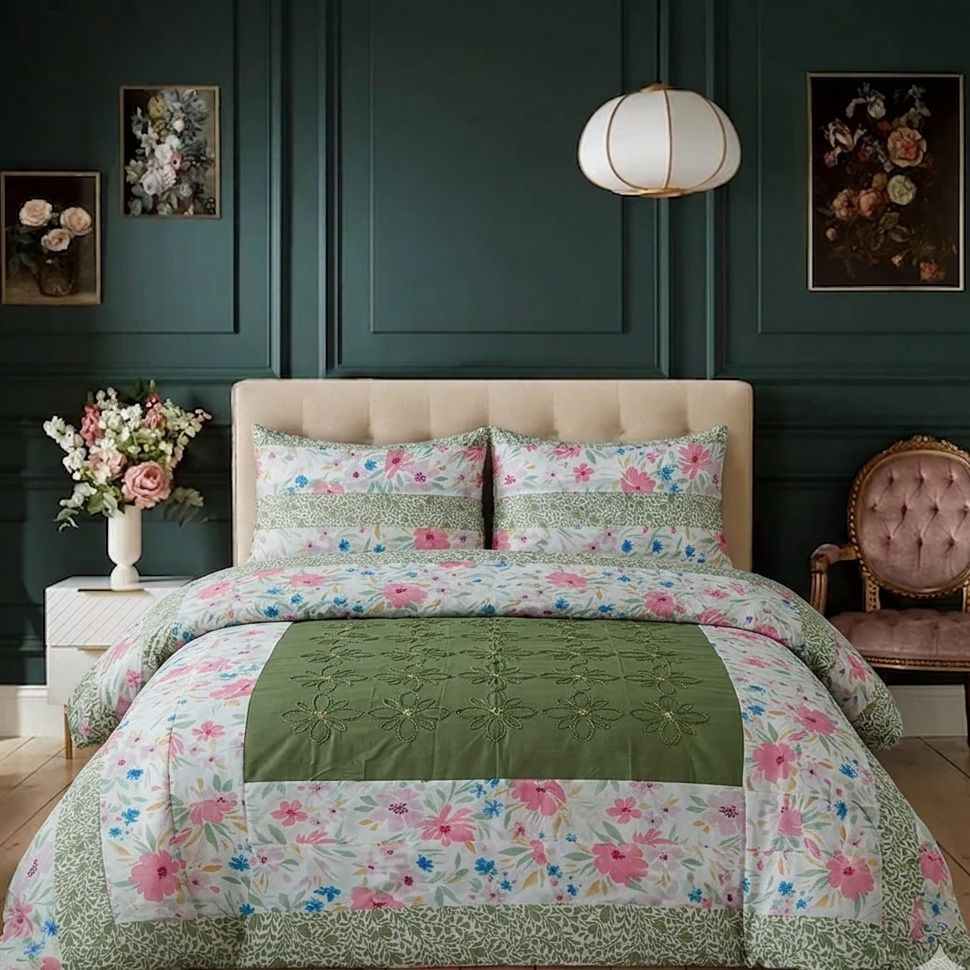 Floral quilt set on a bed in a bedroom with dark green walls and a lamp.