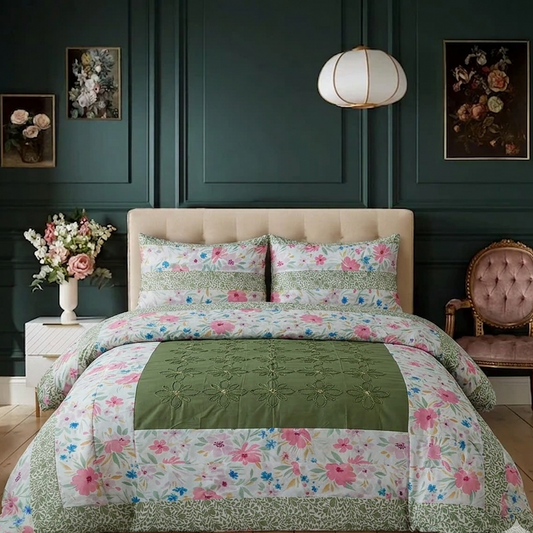 Floral quilt set on a bed in a bedroom with dark green walls and a lamp.